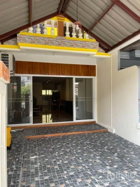 Townhouse for rent in Bang Na, Bangkok - Covered carport with tiled floor and sliding glass entry at a Bang Na townhouse.