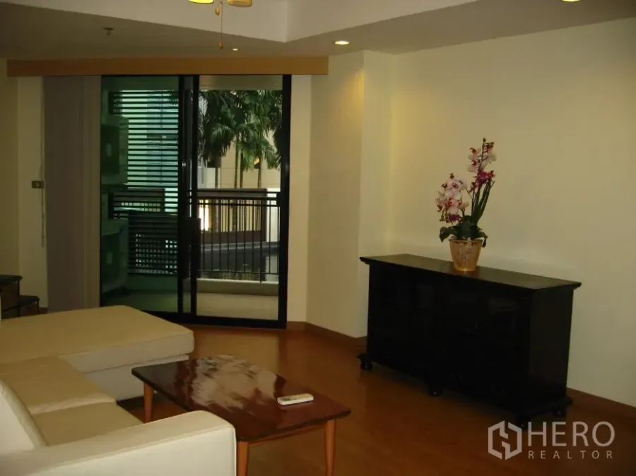 Condominium for rent in Watthana, Bangkok - Bright living room with sectional sofa, coffee table and balcony access with pool view.