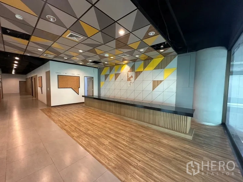 Office Space for rent in Ratchathewi, Bangkok - Front desk with feature wall of yellow-grey triangles and full-height glass.