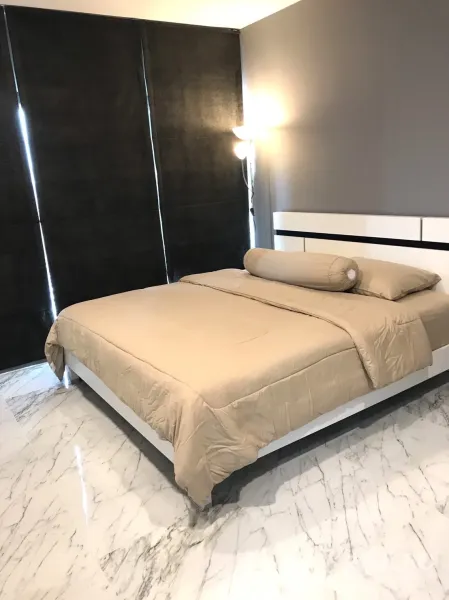 Condominium for rent in Khlong Toei, Bangkok - Cozy bedroom with beige bedding, blackout curtains and glossy marble-look floor.