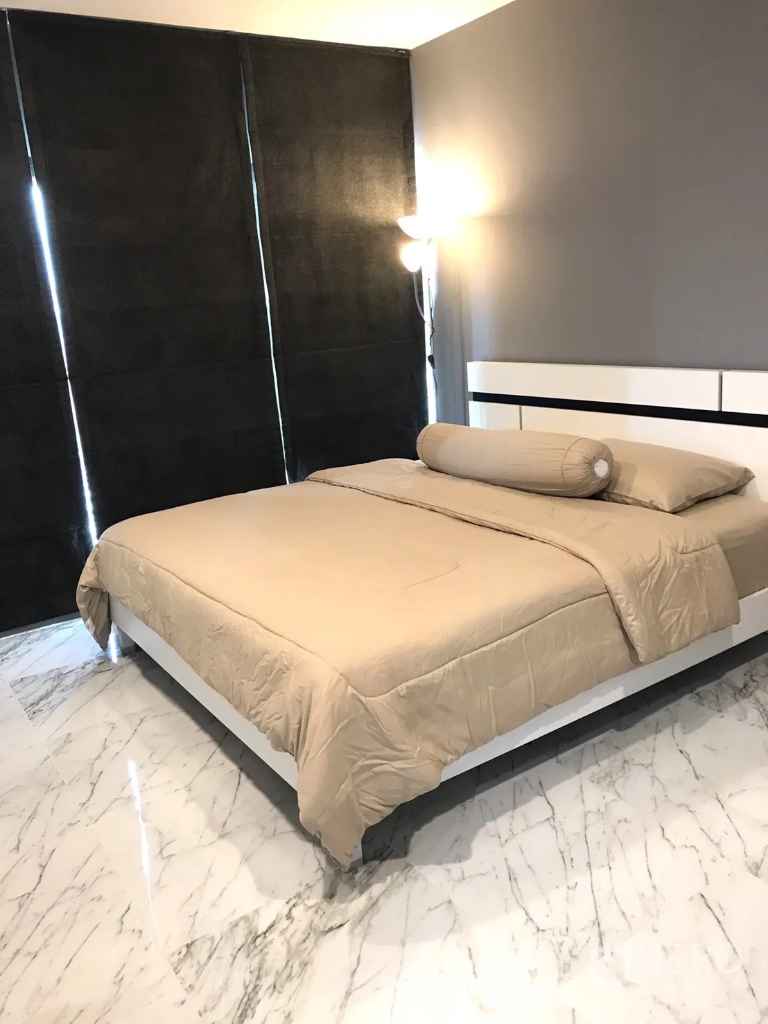 Condominium for rent in Khlong Toei, Bangkok - Cozy bedroom with beige bedding, blackout curtains and glossy marble-look floor.