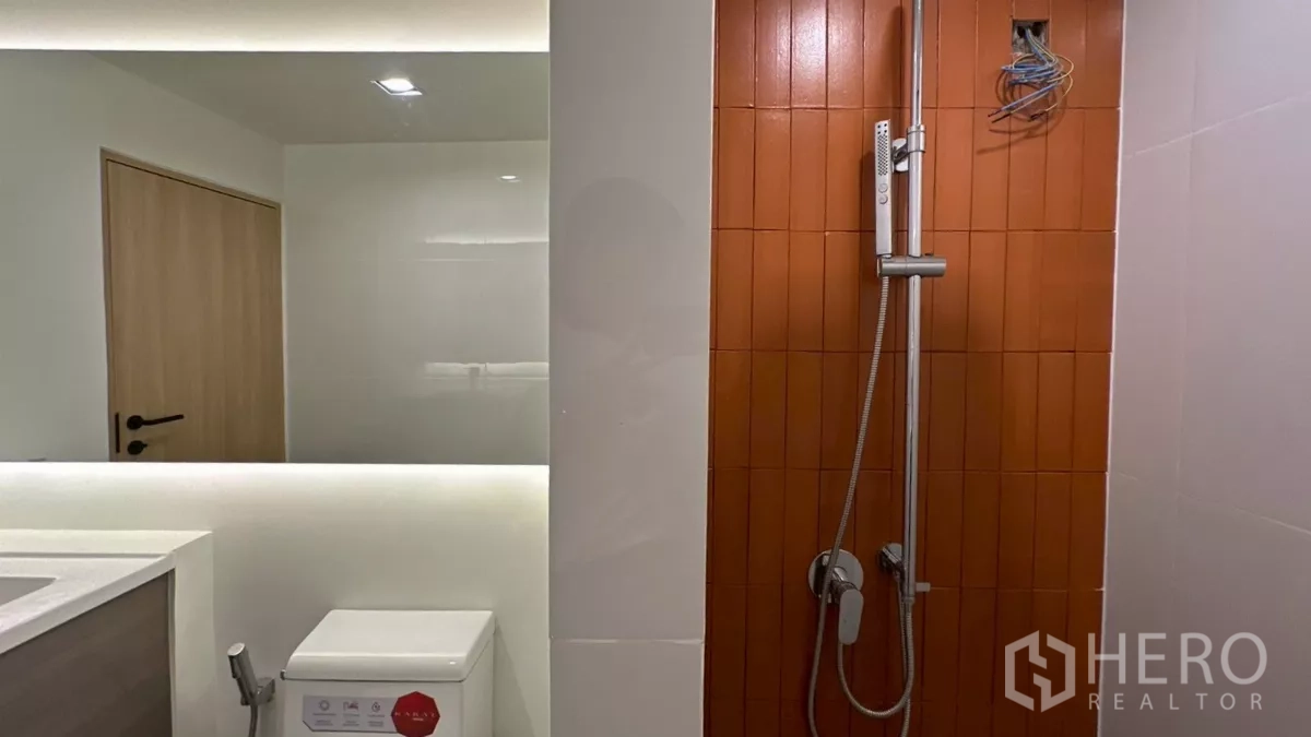 带办公室的家 出租在Watthana, Bangkok - 淋浴区配手持花洒，旁有橙色特色墙与坐便。