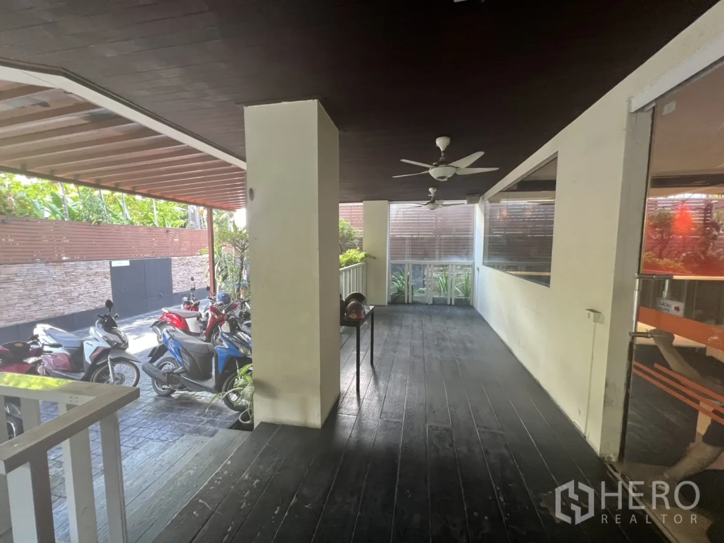 Retail Space for rent in Khlong Toei, Bangkok - Covered walkway beside motorbike parking with ceiling fans and glass windows.