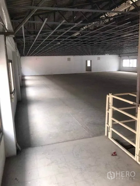 Factory for rent in Bang Bua Thong, Nonthaburi - Wide open floor beneath a metal roof structure with windows along the wall.