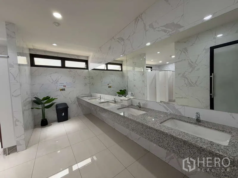 Office Space for rent in Huai Khwang, Bangkok - Clean restroom with marble-effect tiles, long granite countertop, multiple sinks and large mirror.