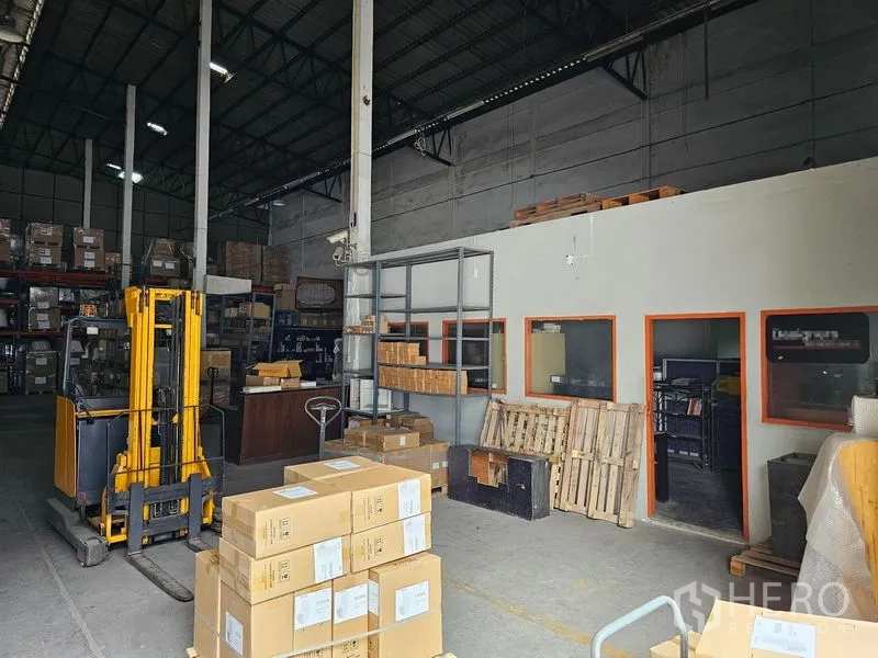 货栈 出租在Khlong Toei, Bangkok - 存储区配黄色堆高机，内部办公室窗口、托盘与箱件清晰可见。