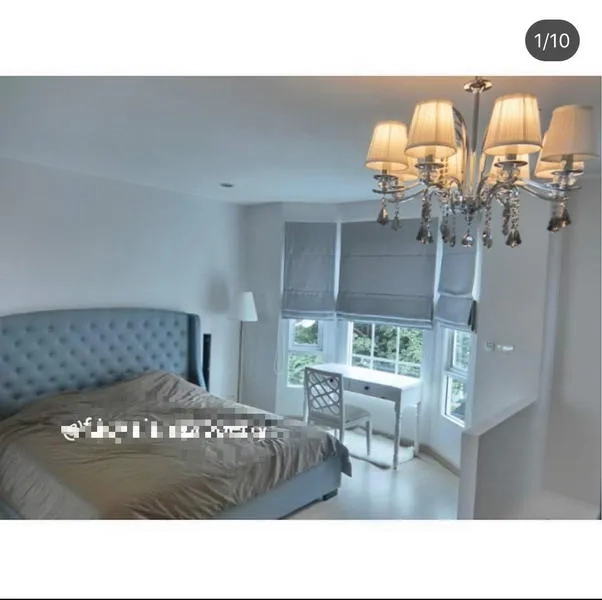 Townhouse for rent in Bang Kapi, Bangkok - Master bedroom with bay windows, chandelier and study desk overlooking greenery.