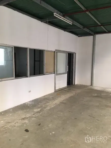 Warehouse for rent in Suan Luang, Bangkok - Internal office room with white walls, windows, and a sliding glass door inside the warehouse.