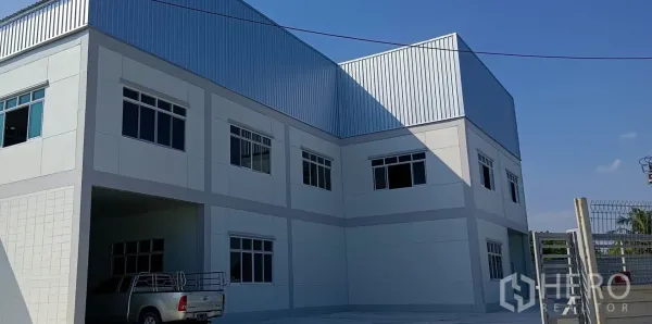 Warehouse for rent or sale in Lam Luk Ka, Pathum Thani - Close view of the warehouse façade with metal cladding and multiple windows.