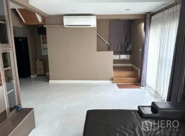 Detached House for rent in Suan Luang, Bangkok - Open-plan living area with glossy tile floors, staircase and wide sliding glass doors.