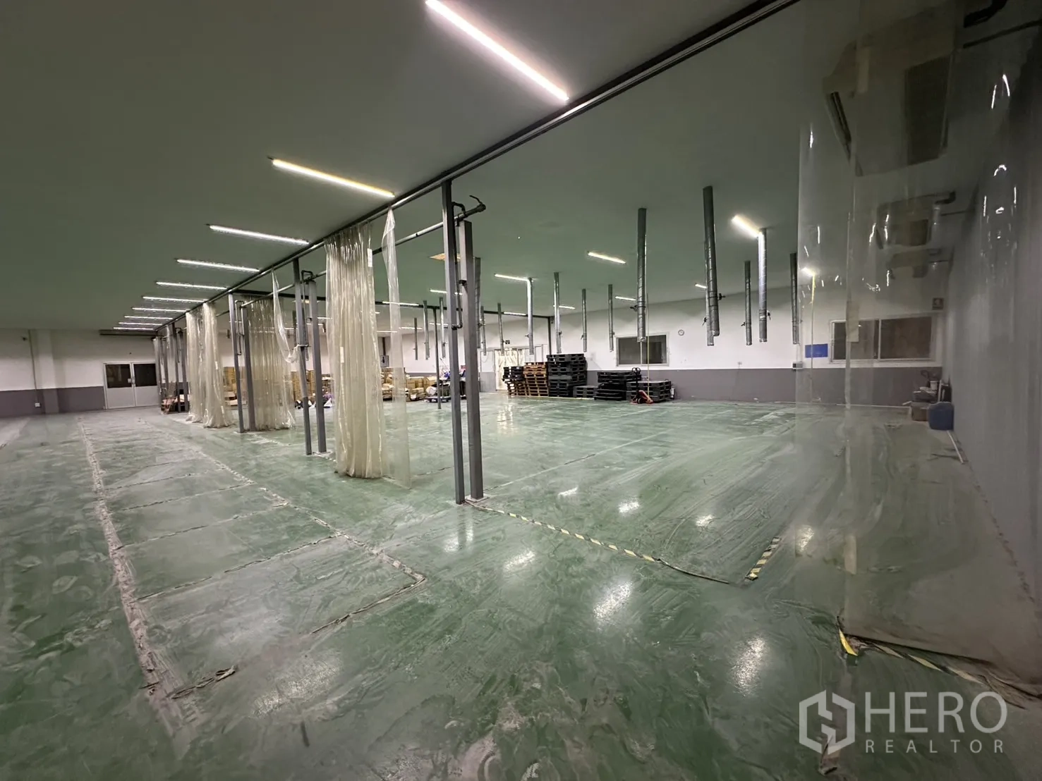 Factory for rent - Close view of strip-curtain workstations and polished epoxy flooring.