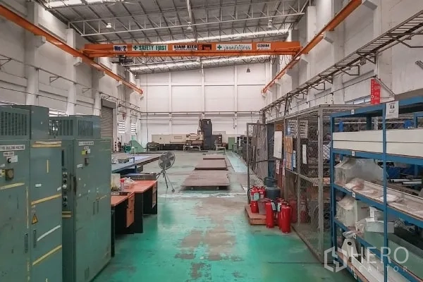 Factory for sale in Rayong - Production area with storage racks, safety equipment and dual overhead cranes.