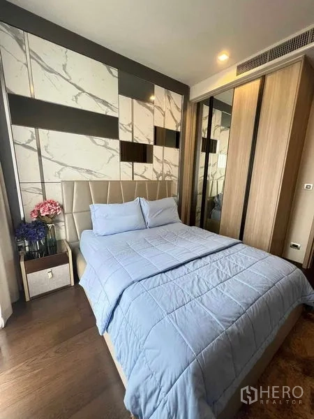 Condominium for rent or sale in Watthana, Bangkok - Cozy second bedroom with feature wall, blue duvet and mirrored wardrobe for storage.