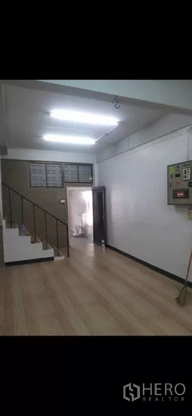 Shophouse for rent or sale in Phra Khanong, Bangkok - Ground floor workspace with staircase and white walls leading to upper levels.