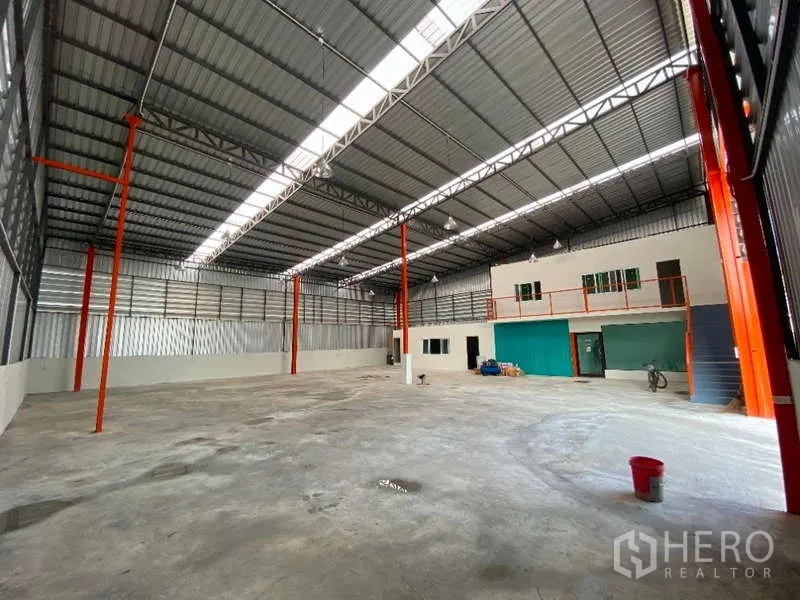 货栈 出租在Don Mueang, Bangkok - 宽敞仓库地面，设夹层办公区、橙色立柱与大型卷闸门。