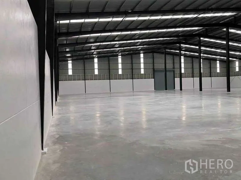 Warehouse for rent or sale in Nikhom Phatthana, Rayong - Side angle of the warehouse highlighting smooth concrete flooring and insulated roofing panels.