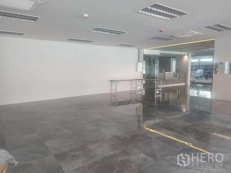 零售空间 出租 - 开放式零售铺面，灰色亮面地砖、吊顶灯和玻璃门面。