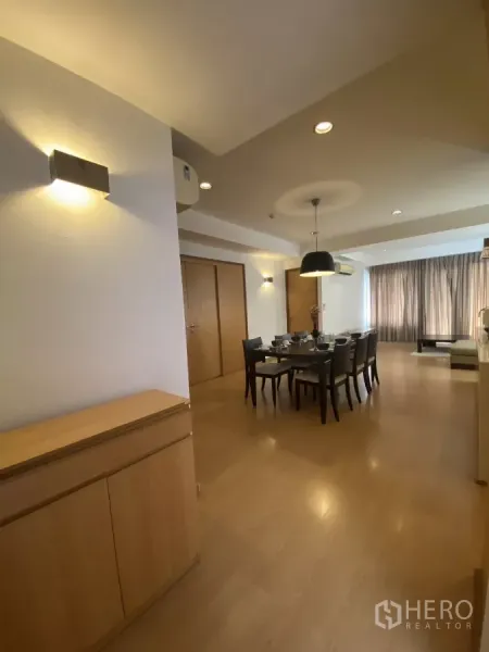 Condominium for rent in Watthana, Bangkok - Hallway view to the dining room with wall sconces and built-in cabinet leading to a bright living area.