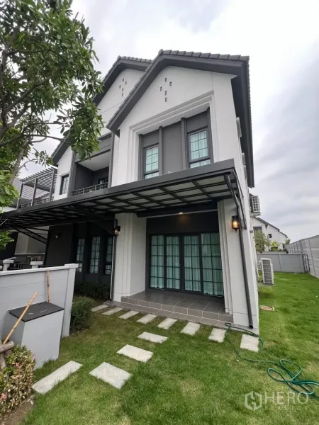 Detached House for rent in Bang Phli, Samut Prakan - Side view showing covered terrace, French doors and a lawn with stepping stones.