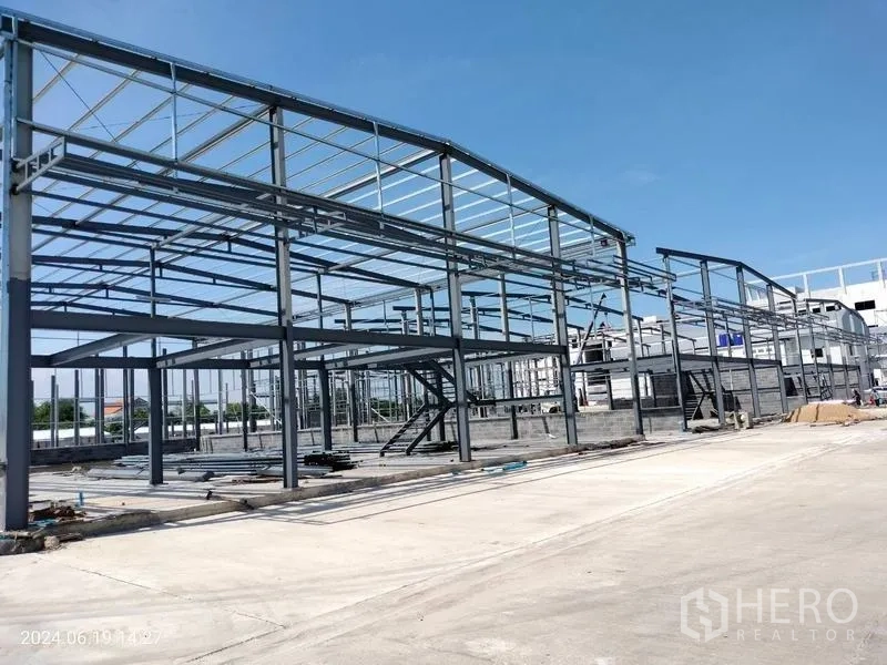 Warehouse for rent in Samut Prakan - Long perspective of high-clearance warehouse skeleton with mezzanine platform and spacious truck yard.