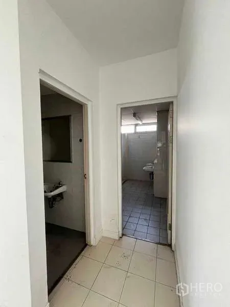 Warehouse for rent in Lat Krabang, Bangkok - Hallway leading to restrooms with tiled floor inside the industrial office area.