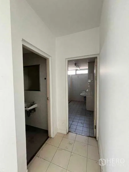 Warehouse for rent in Lat Krabang, Bangkok - Hallway leading to restrooms with tiled floor inside the industrial office area.