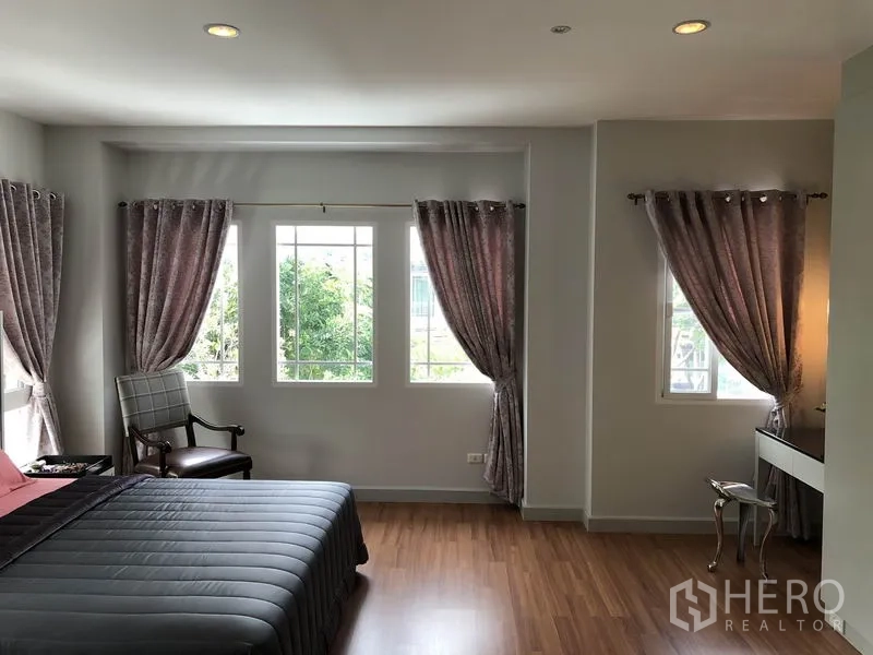 Detached House for rent or sale in Bang Kapi, Bangkok - Spacious master bedroom with wood flooring, large windows and blackout curtains for natural light.