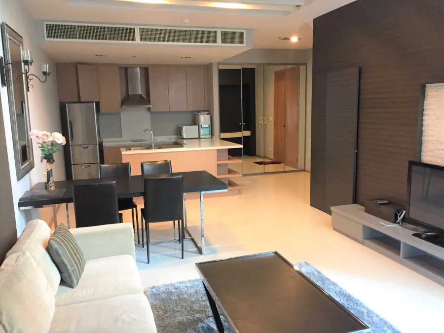 Condominium for rent in Khlong Toei, Bangkok - Open-plan living area with beige sofa, dining table, TV console and a modern kitchen with island and stainless appliances.