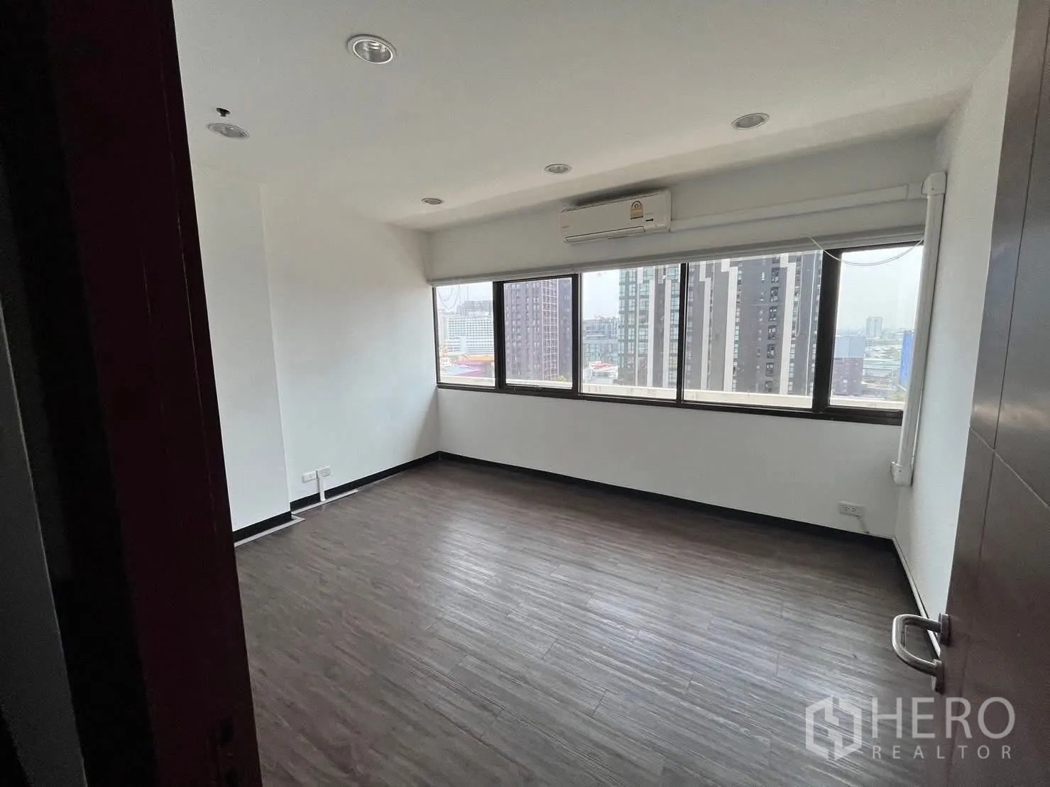 Office Space for rent in Watthana, Bangkok - Bright corner room with long windows, roller blinds and skyline views.