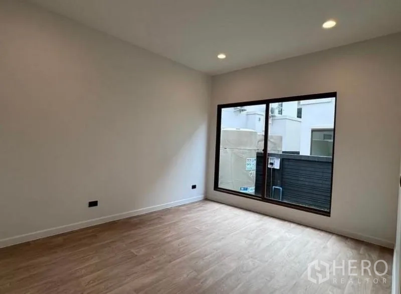 Detached House for rent in Bang Kapi, Bangkok - Ground-floor bedroom with wood-style flooring and a large window.