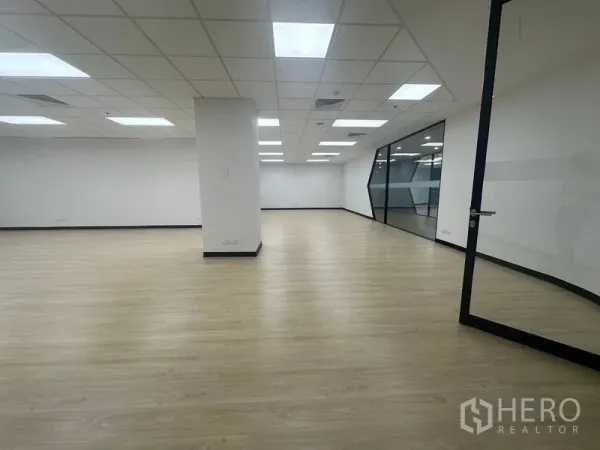 Office Space for rent in Chatuchak, Bangkok - Spacious workspace facing a glass partition and door, with columns and recessed lighting.