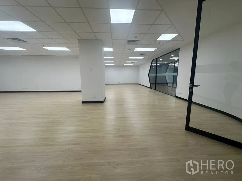 Office Space for rent in Chatuchak, Bangkok - Spacious workspace facing a glass partition and door, with columns and recessed lighting.