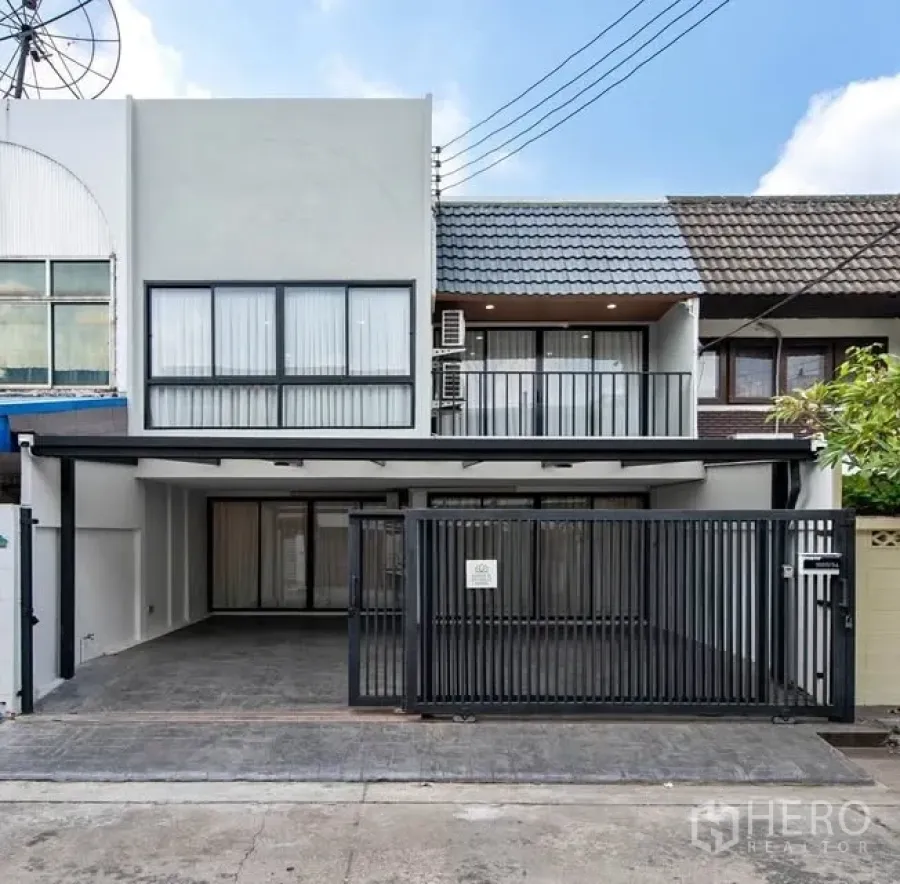 ทาวน์เฮาส์ for rent in Watthana, Bangkok - ทาวน์เฮ้าส์สองชั้นสไตล์โมเดิร์น หน้าบ้านมีประตูรั้วเหล็ก ที่จอดรถในร่ม หน้าต่างบานใหญ่ และระเบียงชั้นบน