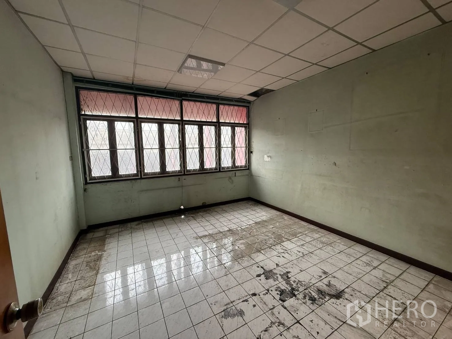 Shophouse for rent in Khlong Toei, Bangkok - Square tiled room with drop ceiling and large grilled windows.