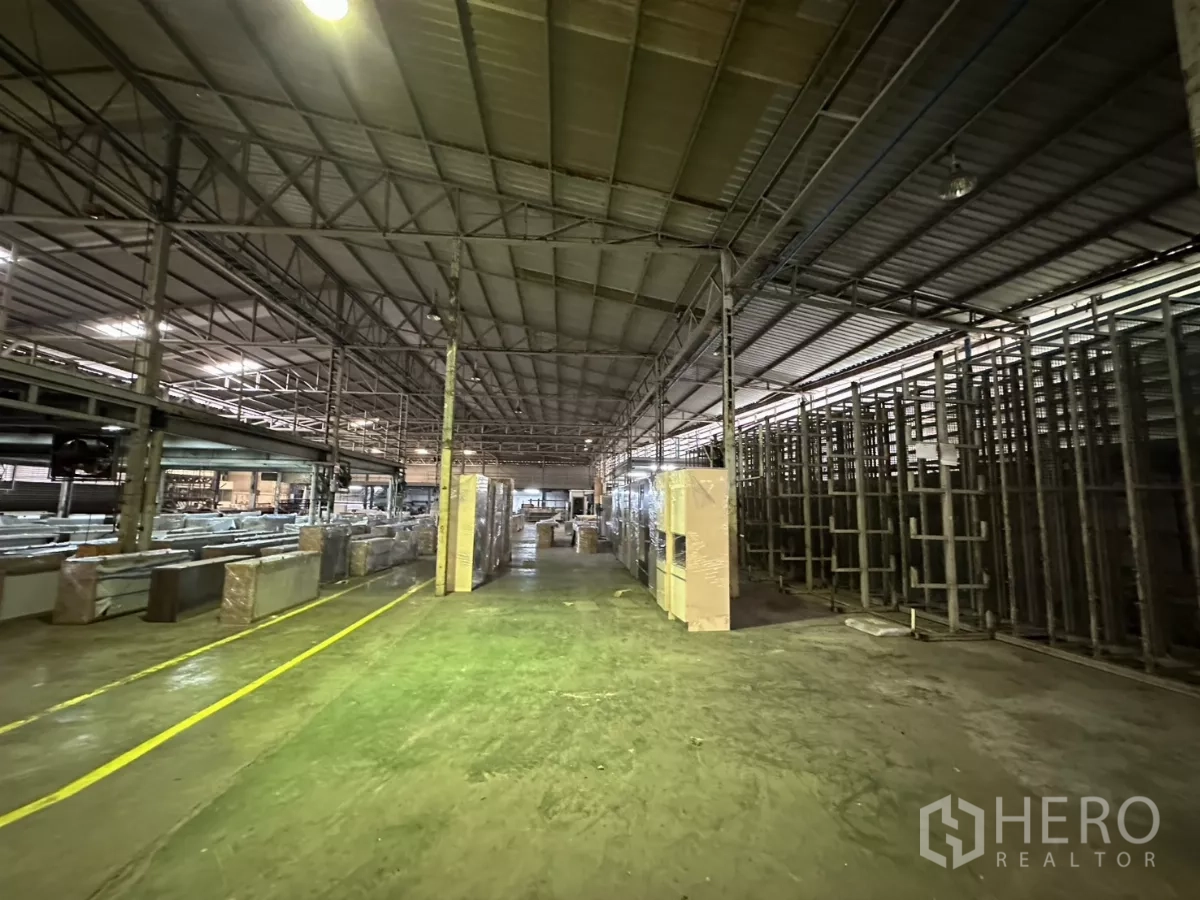 Warehouse for rent in Yan Nawa, Bangkok - Aisle between steel racks and pallets under bright industrial lighting.
