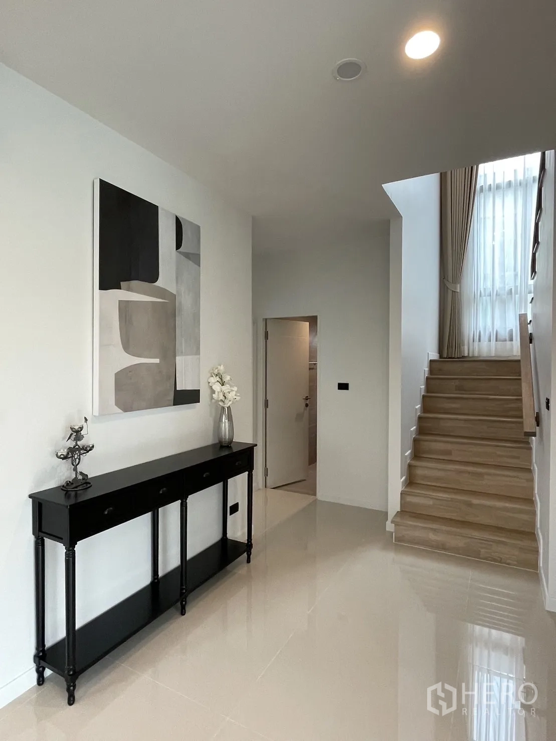 Detached House for rent in Bang Kapi, Bangkok - Entry foyer with staircase, high window, and console table against a white wall.