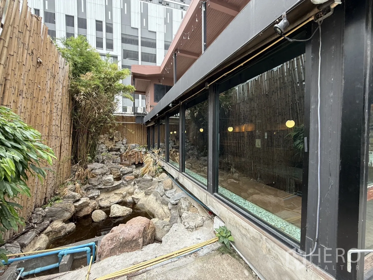 Detached House for rent in Watthana, Bangkok - Side garden with bamboo fence, rock stream and pond beside large glass windows.