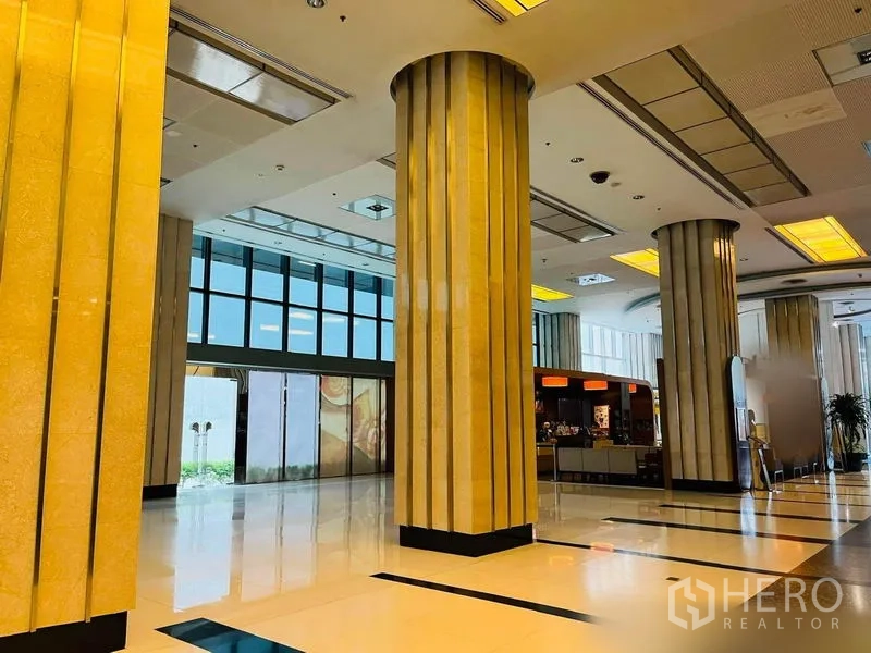 Retail Space for rent in Khlong Toei, Bangkok - Grand retail atrium featuring tall fluted columns, glossy tiled floors and illuminated ceiling panels beside a cafe counter.