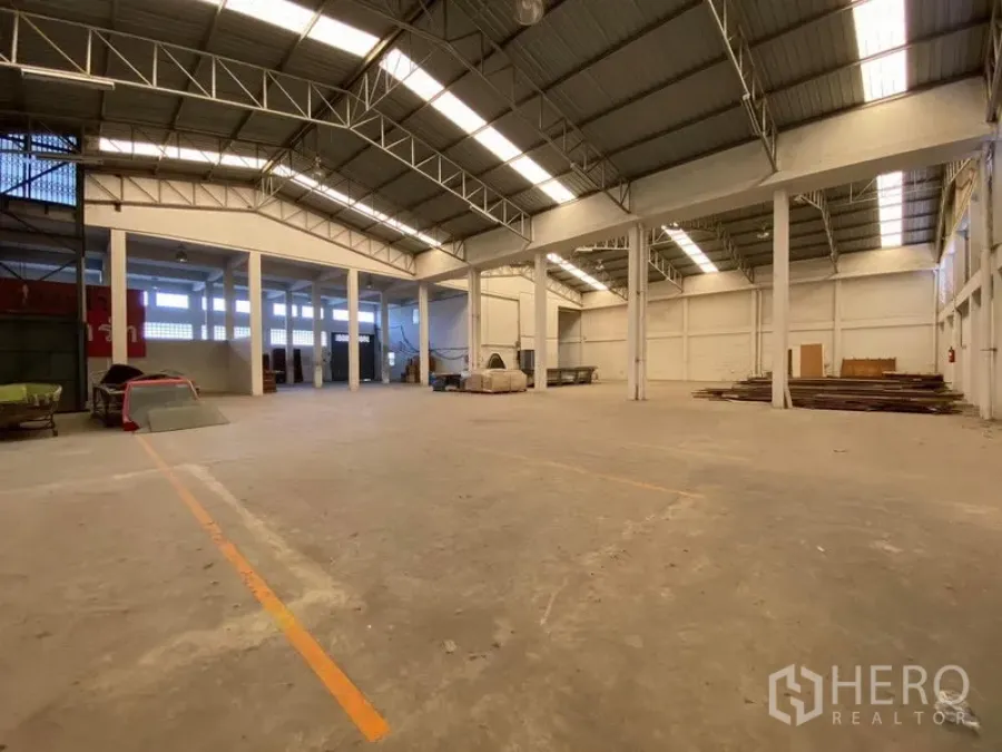 Factory for sale in Bang Phli, Samut Prakan - High-clearance warehouse hall with steel trusses, skylights and marked working zones.
