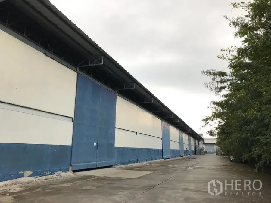 货栈 出租在Bang Phli, Samut Prakan - 蓝白色仓库外立面，宽阔混凝土车道与装卸区，位于邦普里。