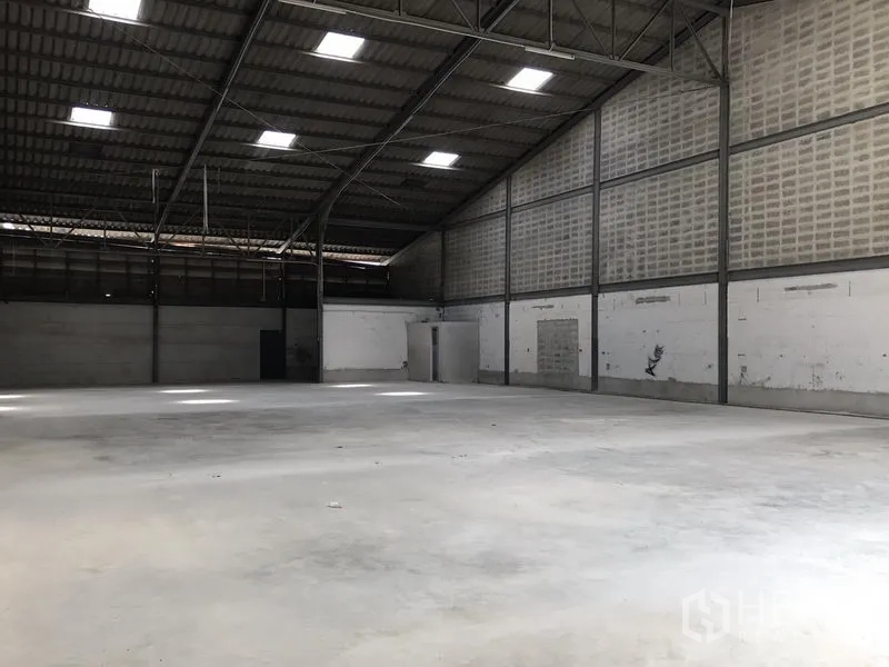 Warehouse for rent in Bang Phli, Samut Prakan - Large warehouse hall with concrete flooring, steel beams and side service doors.