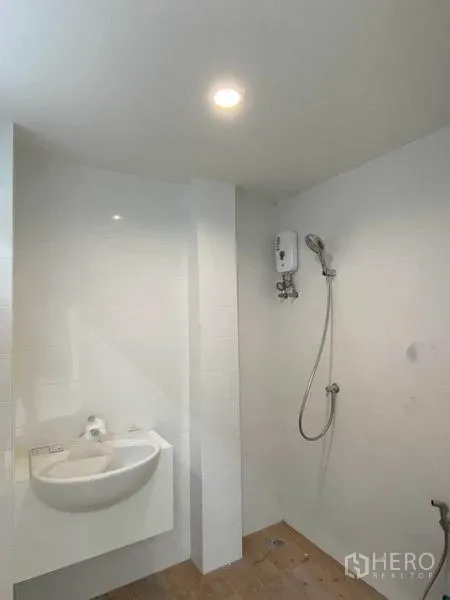 Home Office for rent in Phra Khanong, Bangkok - Compact bathroom with wall‑mounted sink, shower and water heater.