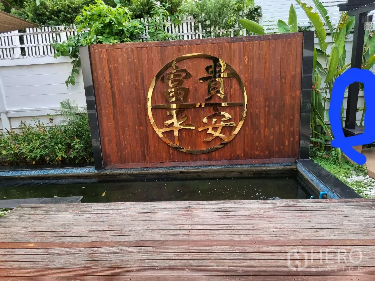Detached House for rent in Bang Kapi, Bangkok - Timber deck beside koi pond and wooden wall with gold round motif.