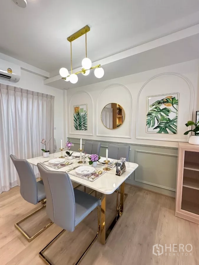 Townhouse for rent in Prawet, Bangkok - Elegant dining area with marble-top table, six gray chairs, gold chandelier and wall molding.