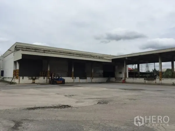 货栈 出租在Pathum Thani - 仓库外观，多个装卸月台与带顶平台，宽阔硬化场地便于大型卡车调头。