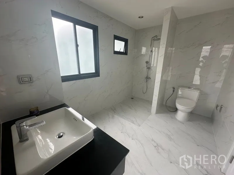 Home Office for rent in Suan Luang, Bangkok - Large marble-tiled bathroom with shower, toilet, and vanity.