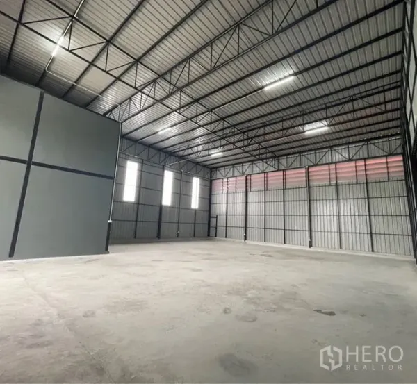 Warehouse for rent in Lam Luk Ka, Pathum Thani - Spacious high-ceiling warehouse interior with steel trusses, skylight panels and smooth concrete floor.