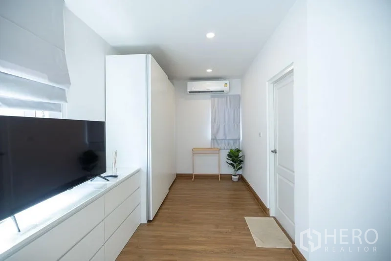 Detached House for sale in Prawet, Bangkok - Long media room with TV, built-in storage, air conditioner and wood floors.