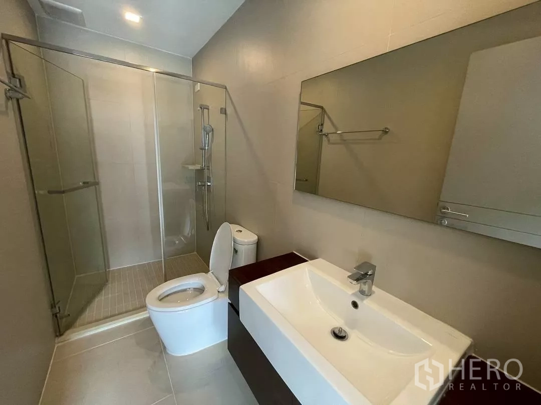 Townhouse for rent in Suan Luang, Bangkok - Modern bathroom featuring a glass-enclosed shower, wide mirror, vanity and toilet.