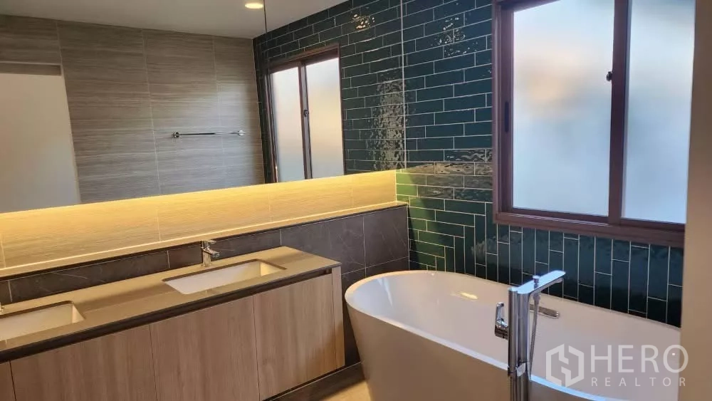 Detached House for rent or sale in Bang Kapi, Bangkok - Bathroom featuring freestanding bathtub, double vanity and emerald tile accent wall.